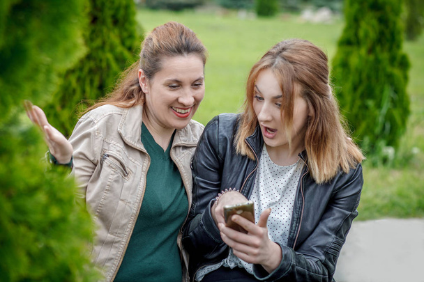 Two amazed women friends sharing social media outdoor - Photo, Image