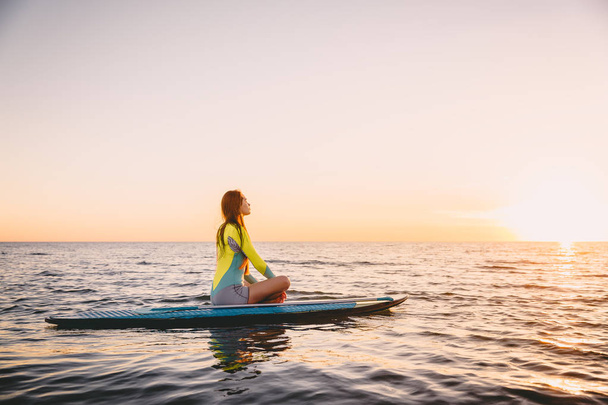 Girl sitting  on paddle board  - 写真・画像