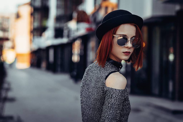 Outdoor portrait of young beautiful fashionable lady walking on the old street. Model wearing wide-brimmed hat and stylish clothes. Girl looking down. Female fashion concept. City lifestyle. - Foto, Imagen