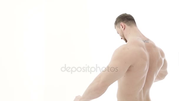 Middellange shot van een gespierde bodybuilder beoefening van de arm met een weerstand band op een witte achtergrond - Video