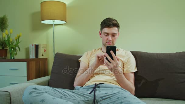 Hombre sentado en el sofá y usando el teléfono móvil
 - Imágenes, Vídeo