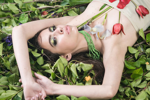 woman with fashionable makeup with flowers on green leaves - Foto, Imagen