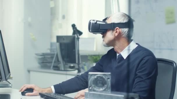 Virtual Reality Engineer Works with VR Glasses On while Simultaneously Doing Programming on His Personal Computer.  - Filmmaterial, Video