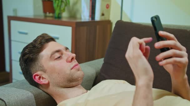 Человек лежит на диване и пользуется мобильным телефоном
 - Кадры, видео