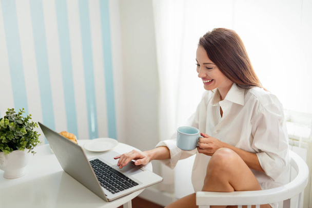 woman using laptop and drinking coffee - Фото, зображення