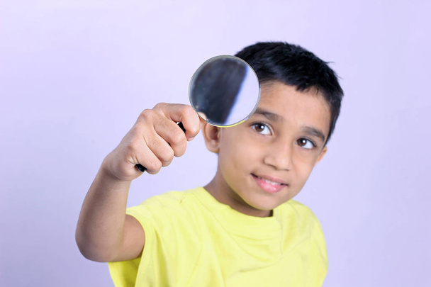маленький індійський хлопчик тримає збільшувальне скло
  - Фото, зображення