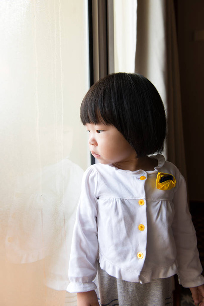 Asiatico bambino guardando il pioggia attraverso finestra
 - Foto, immagini