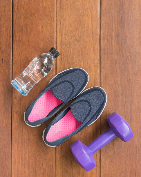 Vista superior del equipo de fitness, la botella de zapatos y la mancuerna en madera
 - Foto, imagen