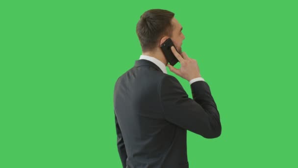 Medium Shot of a Handsome Man Talking on the Phone while Camera Revolves around Him. Shot on a Green Screen Background. - Video, Çekim