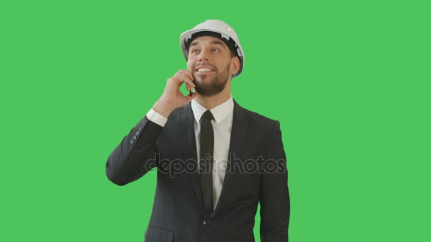 Medium Shot of a Businessman in a Hard Hat Talking on the Phone and Waving Hello to Somebody. Background is Green Screen. - Πλάνα, βίντεο