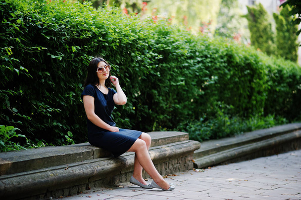Brunette business girl at black dress on sunglasses sitting at b - Fotó, kép