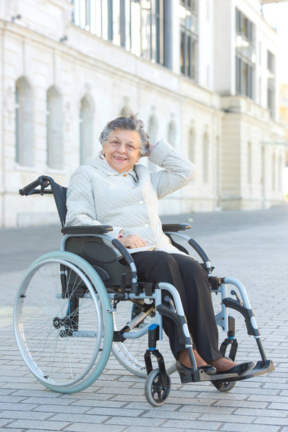 Senior lady in wheelchair in urban setting - Фото, изображение