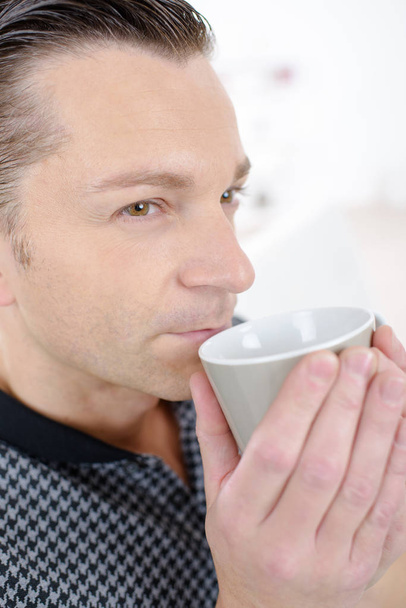 Contemplative man drinking from cup - Foto, afbeelding