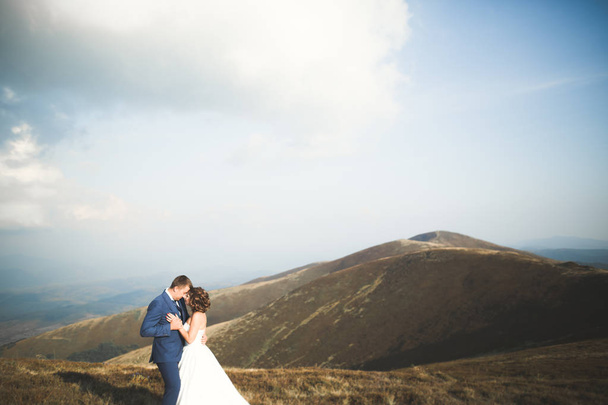 Beautiful gorgeous bride posing to groom and having fun, luxury ceremony at mountains with amazing view, space for text, wedding couple - Foto, afbeelding