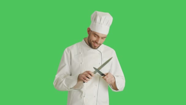 Mid Shot of a Handsome Smiling Chef Sharpening His Knives. Background is Green Screen. - Filmati, video