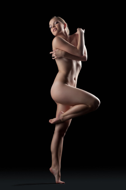 Naked woman posing in dark studio - Foto, Imagen