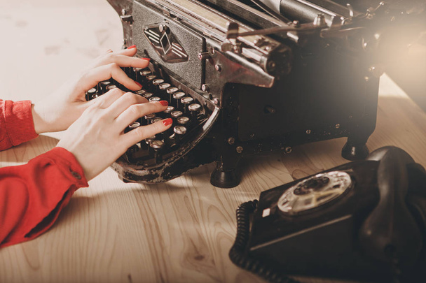 Секретарь старой пишущей машинки с телефоном. Молодая женщина с помощью ти
 - Фото, изображение