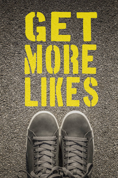 Sneakers with Get More Likes written on the asphalt road - Photo, Image