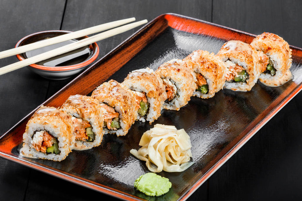 Sushi Roll - Maki Sushi feito de salmão, pepino, abacate e creme de queijo no fundo de madeira escura. Vista superior. Cozinha japonesa
 - Foto, Imagem