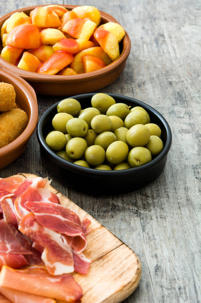 Tradiční španělská tapas. Krokety, olivy, omeleta, šunka a patatas bravas na dřevěný stůl - Fotografie, Obrázek
