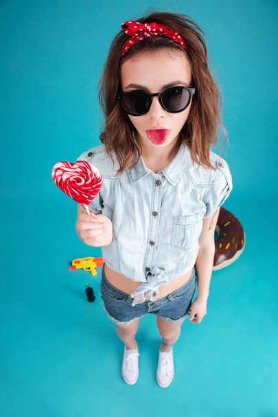 Portrait of a funny stylish girl in sunglasses showing tongue - Photo, Image