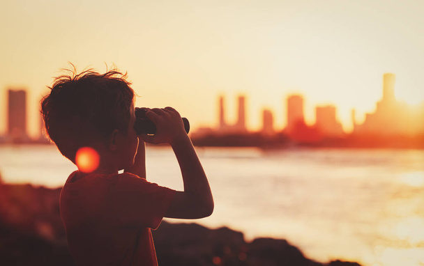 menino olhando para a cidade por do sol
 - Foto, Imagem