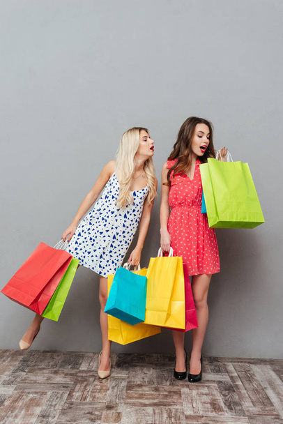 Concentrated young ladies holding shopping bags. - Foto, imagen