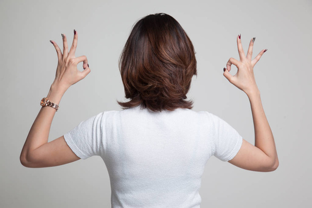 Visão traseira da mulher asiática mostrar duplo sinal de mão OK
. - Foto, Imagem