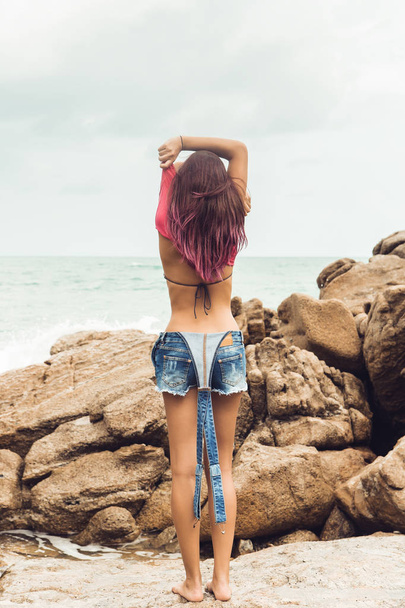 Sexy girl undress on rock beach. - Фото, изображение