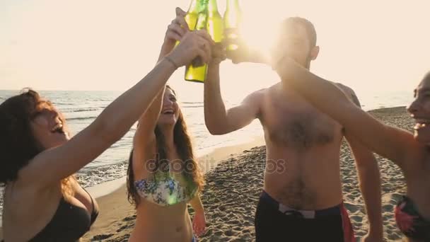 Zomertijd: Glimlachen vrienden Clinks bierflessen op het strand bij de zonsondergang - Video