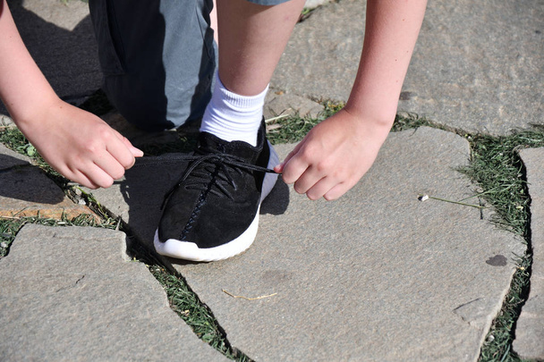 The boy ties the laces on athletic shoes - Фото, зображення