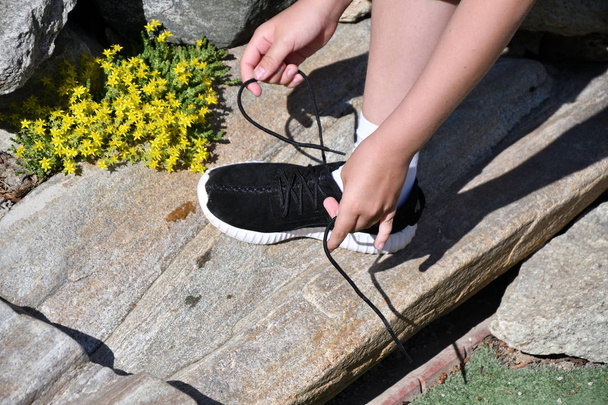 The boy ties the laces on athletic shoes - Photo, Image