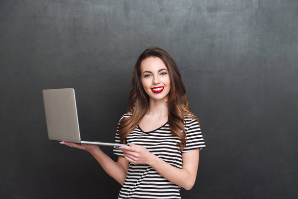 Smiling woman holding laptop computer - Foto, afbeelding