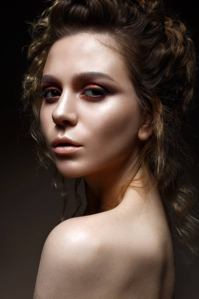 Young girl with bright evening makeup and hairdo with curls. Beautiful model with creative makeup and perfect shining skin. Beauty of the face - Foto, afbeelding