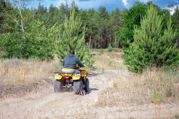 A man riding ATV on a sand road, back view - Photo, Image
