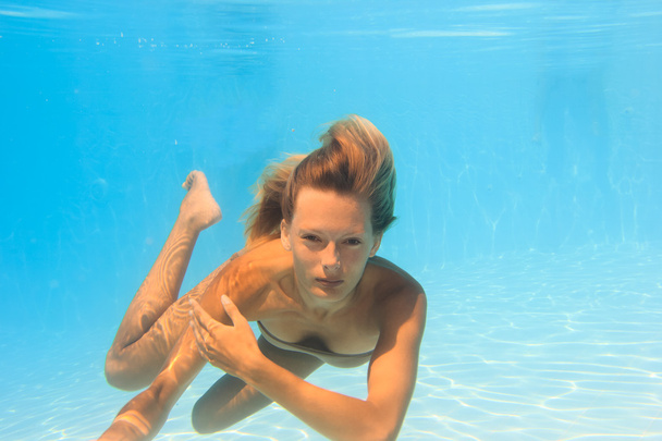 Young woman swimming underwater in the pool - Фото, зображення