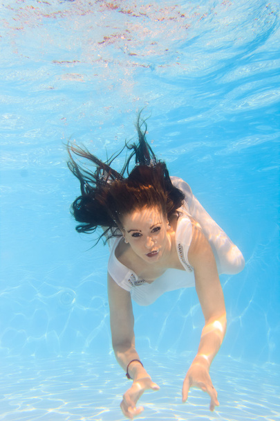Woman in a white dress underwater in swimming pool - Фото, изображение
