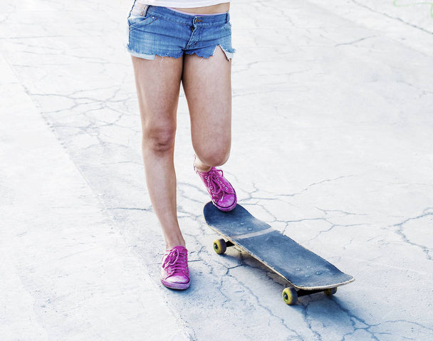 teen girl standing on skateboard  - 写真・画像