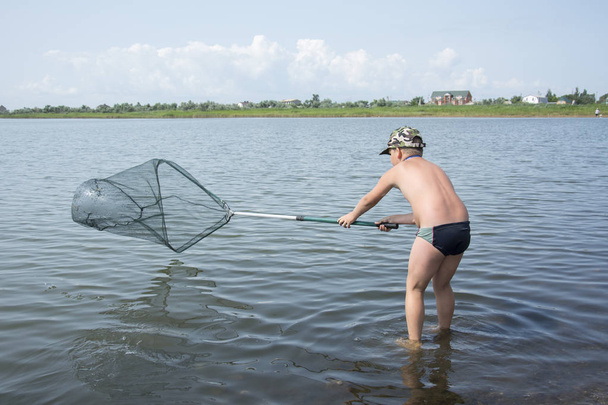 En el verano por la tarde el niño está pescando en el lago wi
 - Foto, imagen