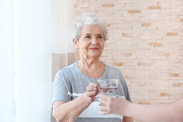 δίνοντας ποτήρι νερό σε ηλικιωμένη γυναίκα - Φωτογραφία, εικόνα
