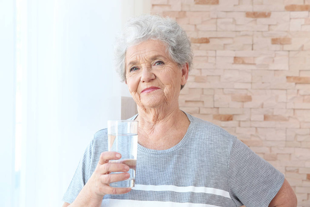 Elderly woman holding glass of water - Foto, Imagen