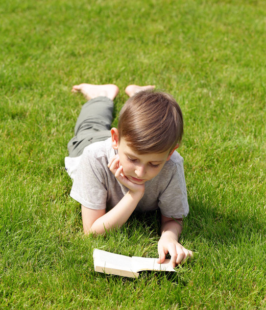 Симпатичный блондин читает книгу в парке на открытом воздухе
 - Фото, изображение