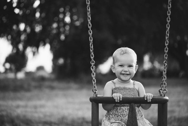 Gelukkig kind meisje lachen en swingen op een schommel  - Foto, afbeelding