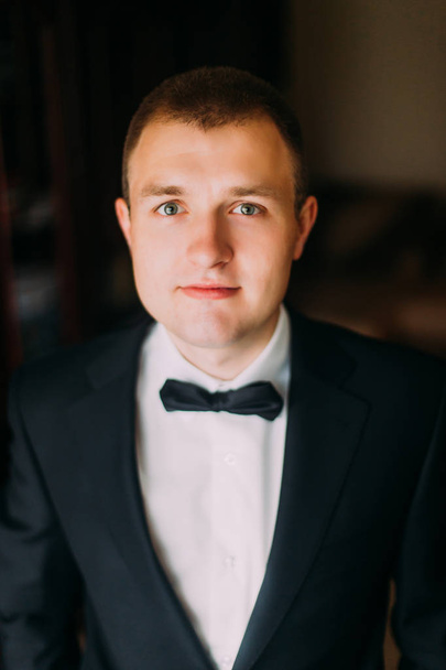 Handsome stylish and confident young man in elegant black suit indoors - Fotografie, Obrázek