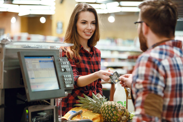 Woman gives credit card to cashier man - Fotoğraf, Görsel