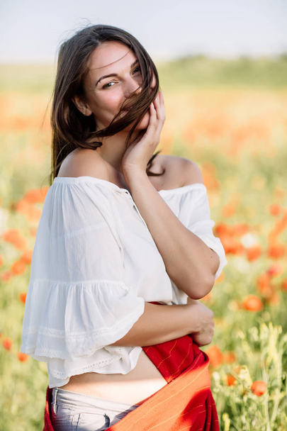 beautiful girl in a poppy field at sunset - Foto, afbeelding