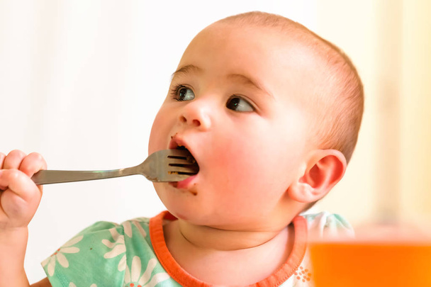 Toddler girl eating food with a fork - Fotoğraf, Görsel