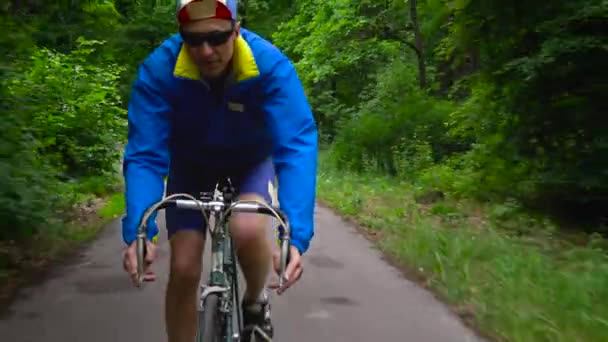 Homem de meia-idade está andando de bicicleta ao longo de uma estrada florestal
 - Filmagem, Vídeo