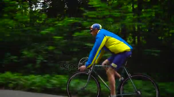 Homem de meia-idade está andando de bicicleta ao longo de uma estrada florestal
 - Filmagem, Vídeo