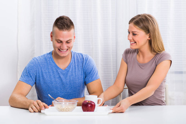 Wife giving breakfast to her husband - 写真・画像
